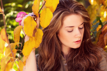 Naklejka na ściany i meble Beautiful model with autumn leaves and fall yellow garden backgr