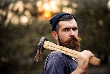 Severe bearded man with an ax at sunset