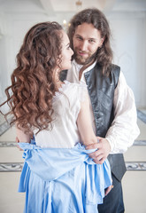 Handsome man in medieval costume undress beautiful woman