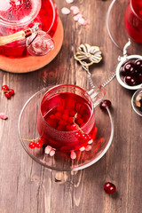 Hot berry tea in glass cups and teapot over rustic wooden background. Winter or fall concept. Selective focus