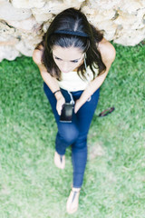 Beautiful young woman lying on the grass in a park with a smart
