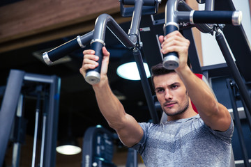 Bodybuilder doing exercise on fitness machine in gym