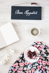 Cup of coffee with dessert and notebook on the table