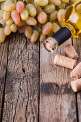 Bottle of white wine, grape and corks on wooden table.selective focus