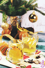 Hot mulled white wine with fruits and spices in glass cups on wooden table. Xmas or new year background. Selective focus