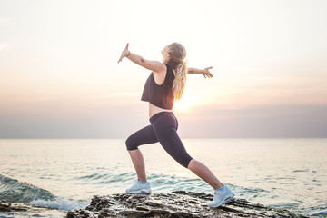  Fitness sport model smiling happy doing exercises during outdoor work out on sunrise. Beautiful caucasian female training outside on seaside in the morning