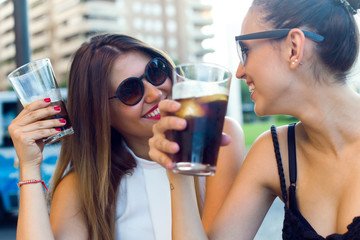 Beautiful young women drinking refreshment in the street. - obrazy, fototapety, plakaty