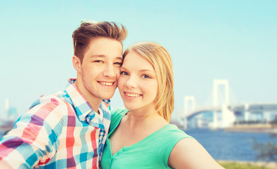 smiling couple taking selfie over bridge