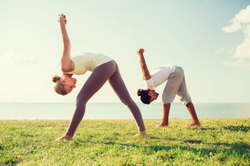smiling couple making yoga exercises outdoors