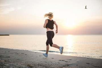 Running woman. Female runner jogging during the sunrise on beach.