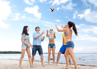 group of happy friends playing beach ball