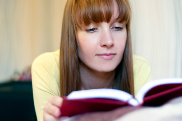 Red head woman reading book at home