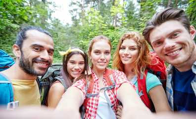 friends with backpack taking selfie in wood