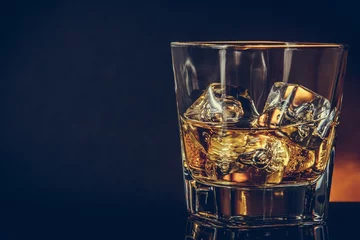 Papier Peint photo autocollant Alcool glass of whiskey on black background with reflection, warm atmosphere