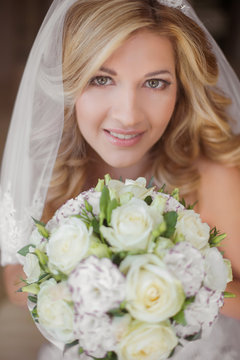 Beautiful smiling bride girl with wedding bouquet of flowers.