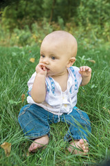 beautiful baby in embroidery on the green grass in the park