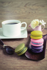 Colorful macaroons and a cup of coffee on wooden table