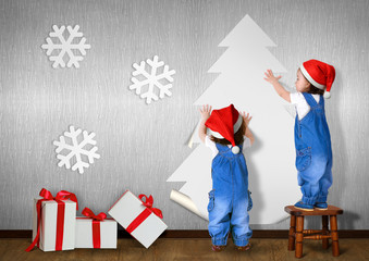 Funny Little twins dressed Santa hat, glue Christmas tree on wal
