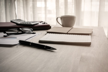 Cup of coffee on wooden desk and stack of documen