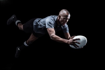 Sportsman jumping for catching rugby ball