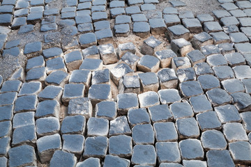 Damaged cobblestone road pavement with sand