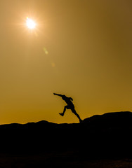 Silhouette Shadow of man jumping on the mountain with sun flare 