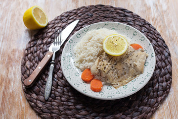 white fish served at the table with lemon and rice