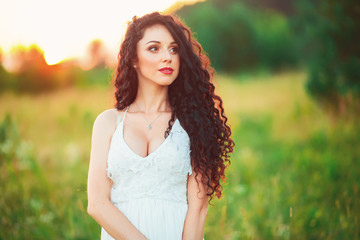 beautiful young girl in a field in white dress has beautiful lon