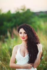 Naklejka premium beautiful young girl in a field in white dress has beautiful lon