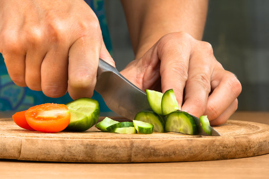hands chopping cucumber for salad