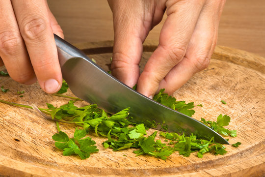 hands chopping parsley leaves on the cutting board