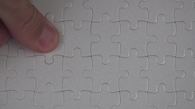 Male hand putting a missing piece and solving blank white jigsaw puzzle, 4k uhd footage, 2160p, 3840x2160