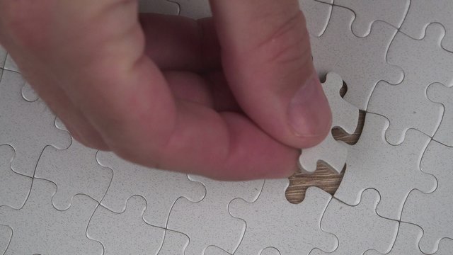 Male hand putting a missing piece and solving blank white jigsaw puzzle, 4k uhd footage, 2160p, 3840x2160