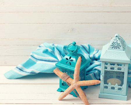 Marine item, lanterns  and blue towel  o white wooden background