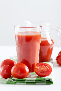 Fresh red tomatoes and tomato juice in glass on wooden table