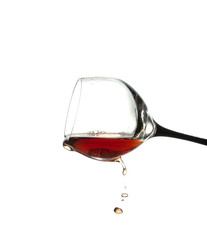 stream of wine being pouring from the glass isolated on the white background
