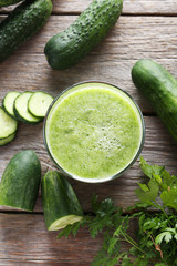 Glass of fresh cucumber juice on grey wooden table