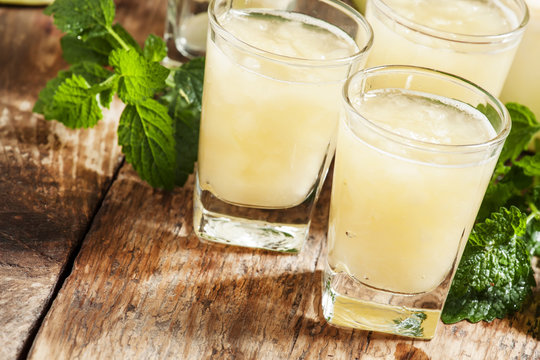 Melon juice in a glass, mint  and slices of melon on a wooden ba