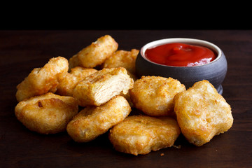 Pile of golden deep-fried battered chicken nuggets with empty ru