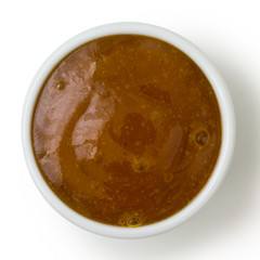 Small white pot of curry sauce dip, from above isolated on white