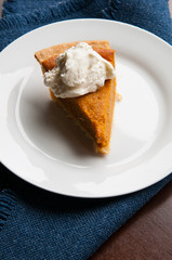 piece of pumpkin pie on a plate with a dollop of whipped cream