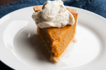 piece of pumpkin pie on a plate with a dollop of whipped cream