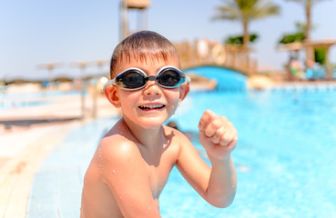 Happy grinning young boy at a swimming pool