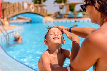 Mother putting sunscreen on her sons face