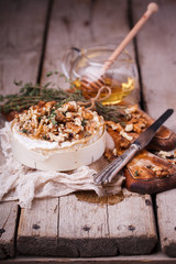 Baked Camembert with honey, walnuts and timanian on an old cutting board.