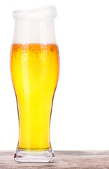 Frosty glass of light beer on a wooden table