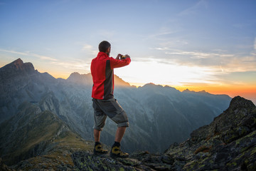Trekker photographing the sunset with his smartphone