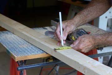 Construction Worker Measuring Wood to Cut