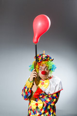 Fototapeta na wymiar Clown with balloon and rifle in funny concept