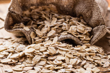 oat flakes cereal in burlap sack on wooden table.